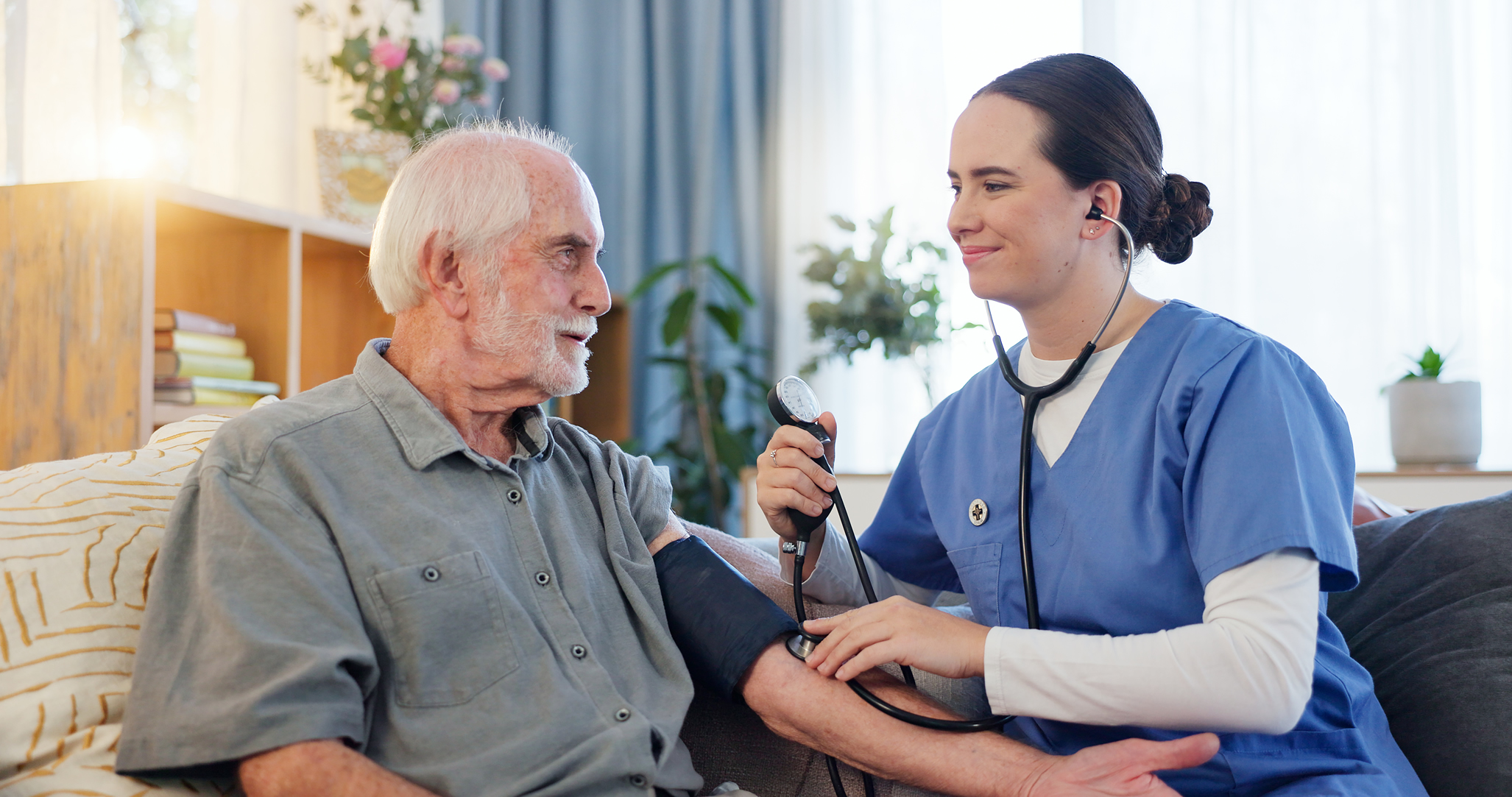 Smiling nurse checking an elderly man’s blood pressure.